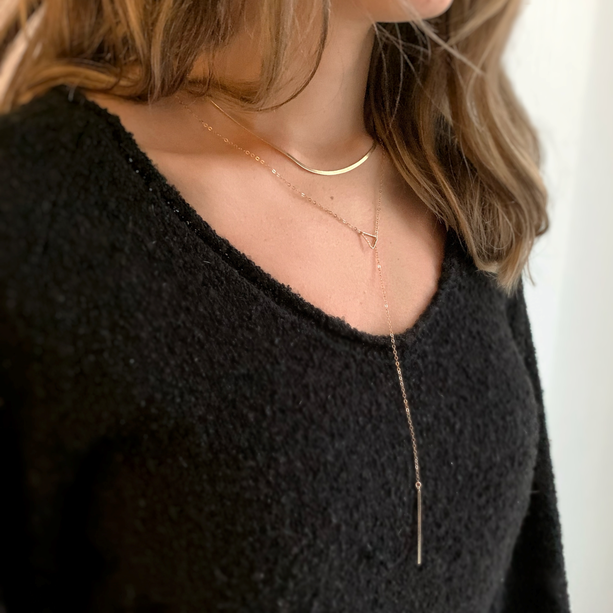 Model wearing gold filled bar lariat necklace and gold herringbone necklace