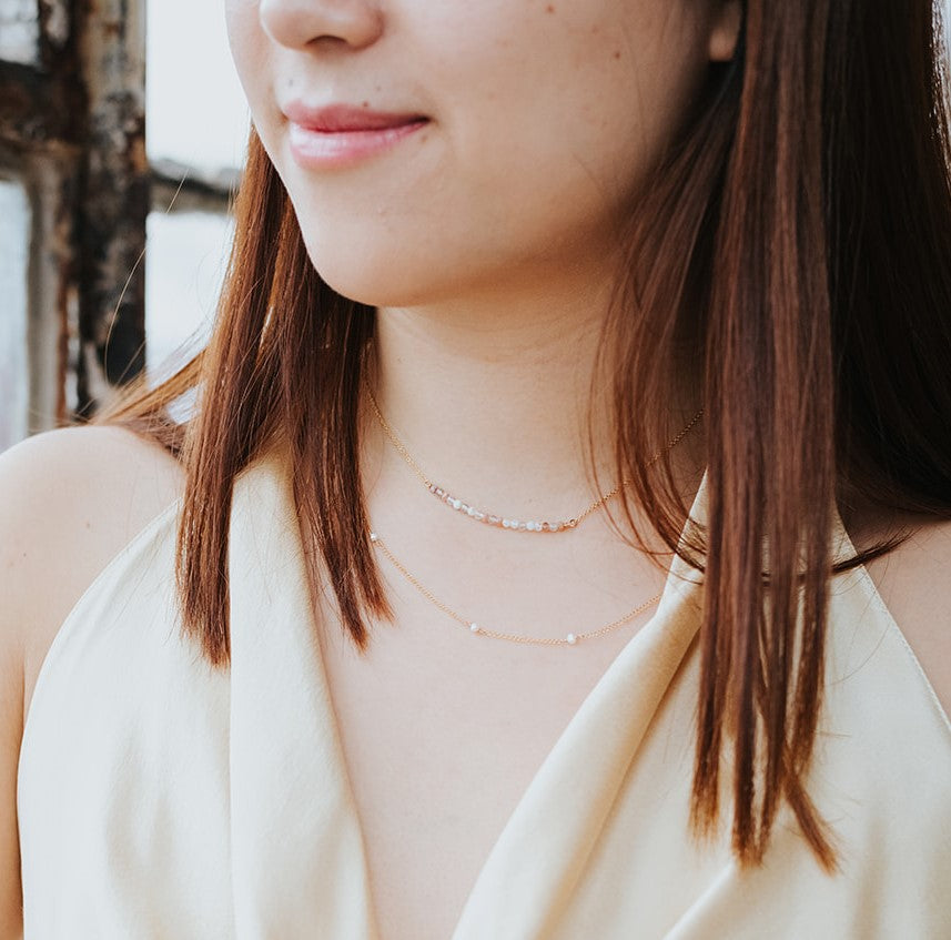 model wearing gold freshwater pearl strand layered with the goddess necklace
