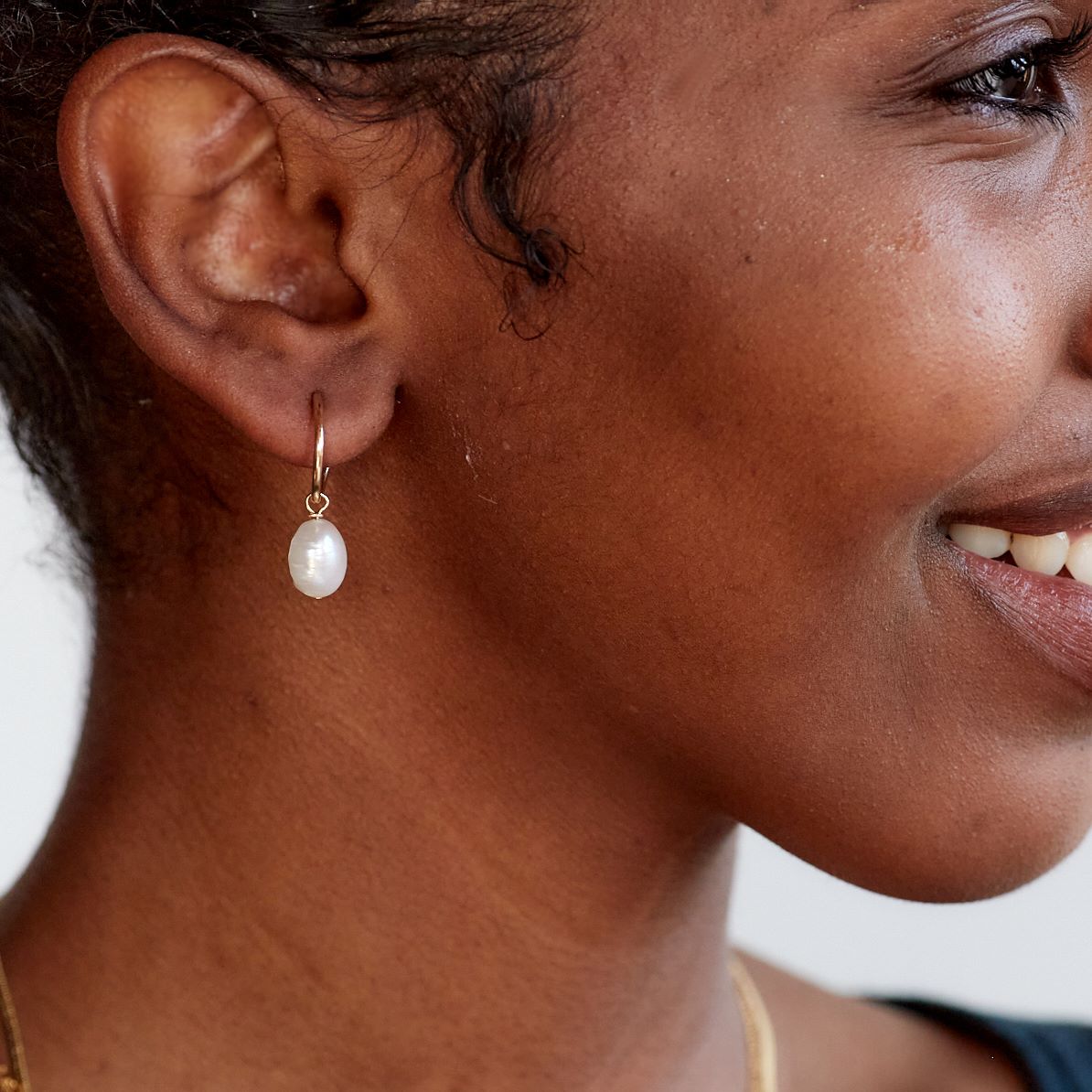 Model wearing baroque pearl small gold hoop earrings