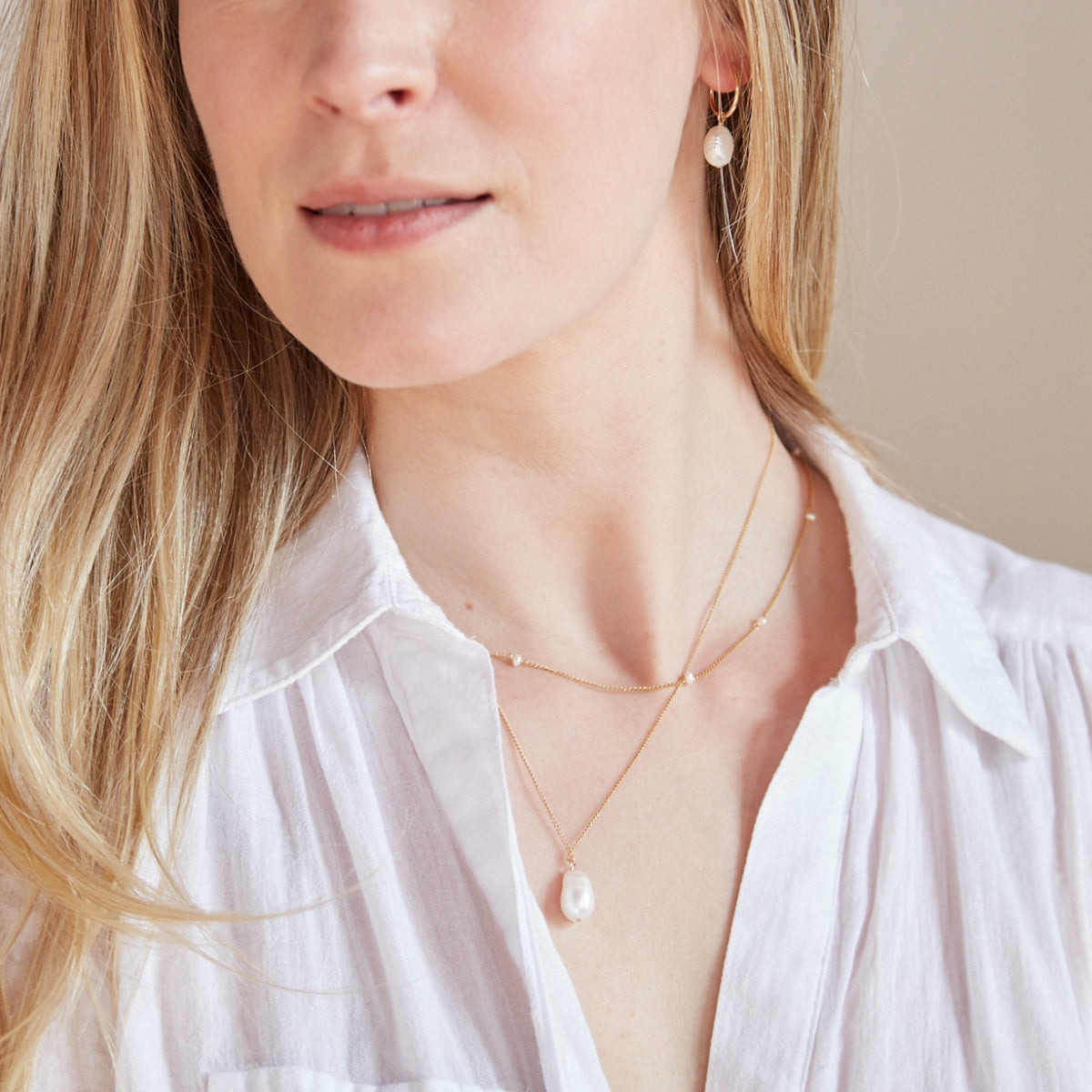 Model wearing baroque pearl earrings and necklace and pearl strand