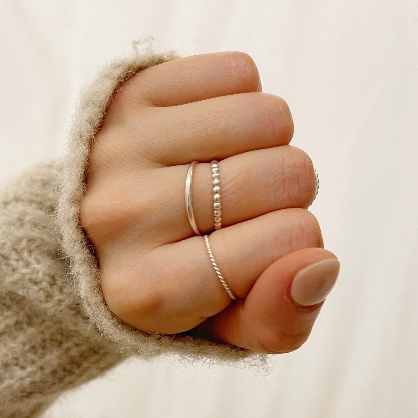 model wearing silver beaded stacking ring, twisted stacking ring, silver band and the square beaded stacking ring