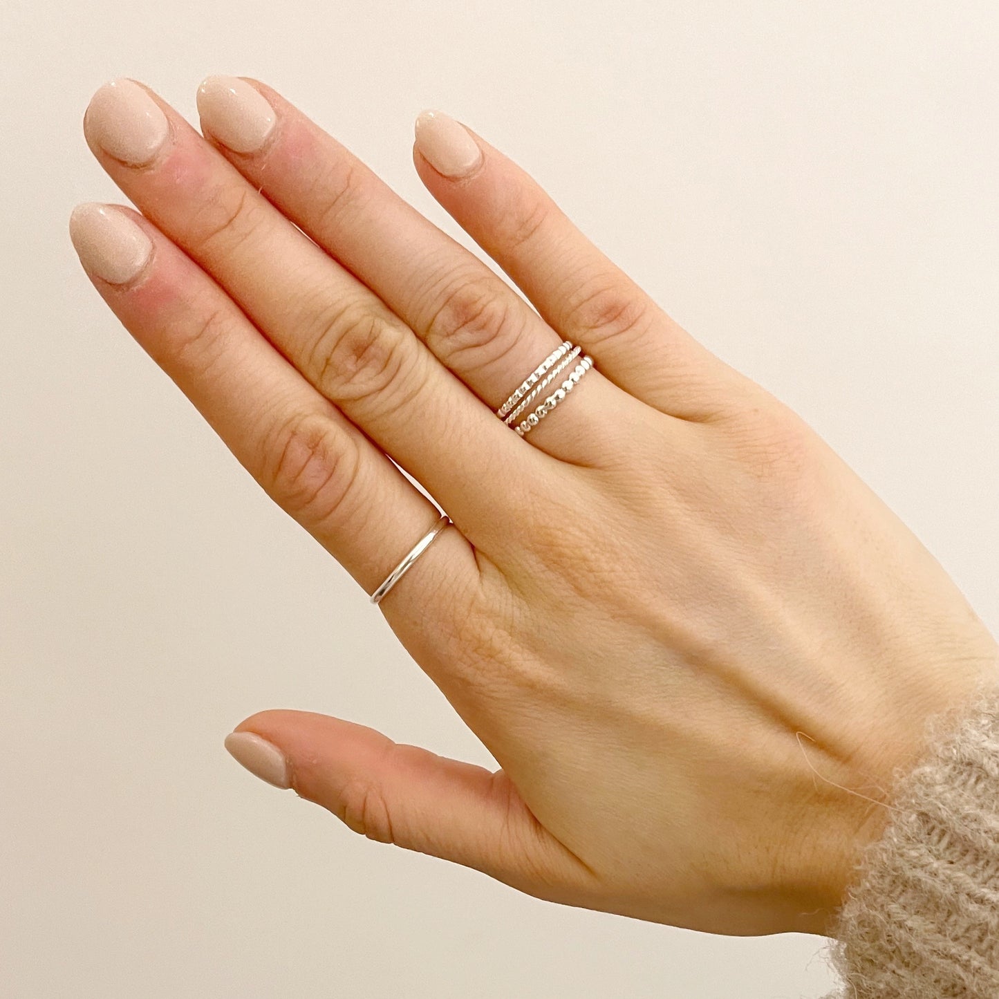 model wearing silver beaded stacking ring, twisted stacking ring, silver band and the square beaded stacking ring