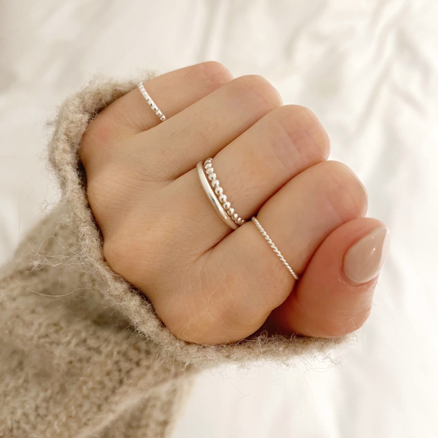 model wearing silver beaded stacking ring, twisted stacking ring, silver band and the square beaded stacking ring