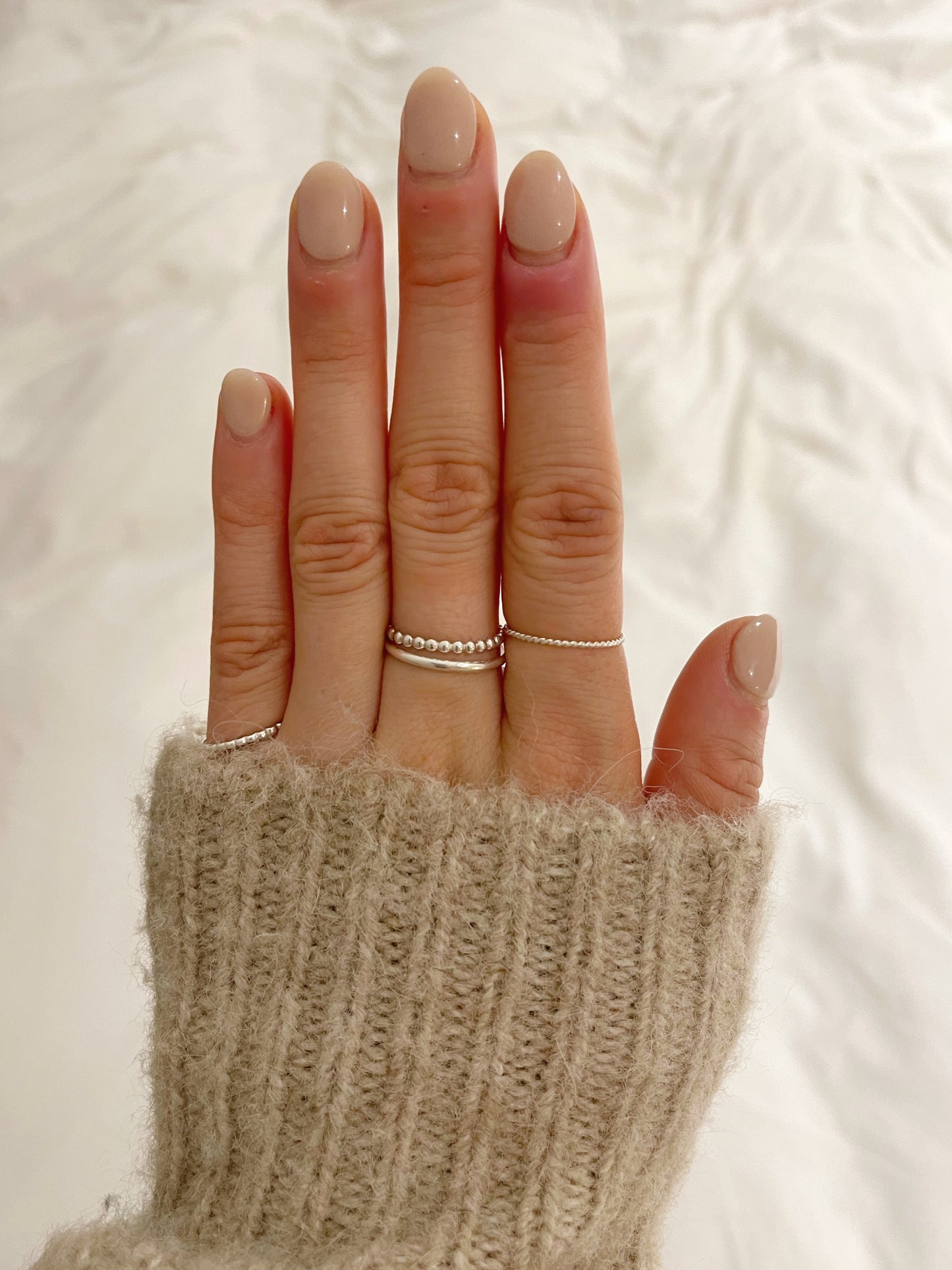 model wearing silver beaded stacking ring, twisted stacking ring, silver band and the square beaded stacking ring